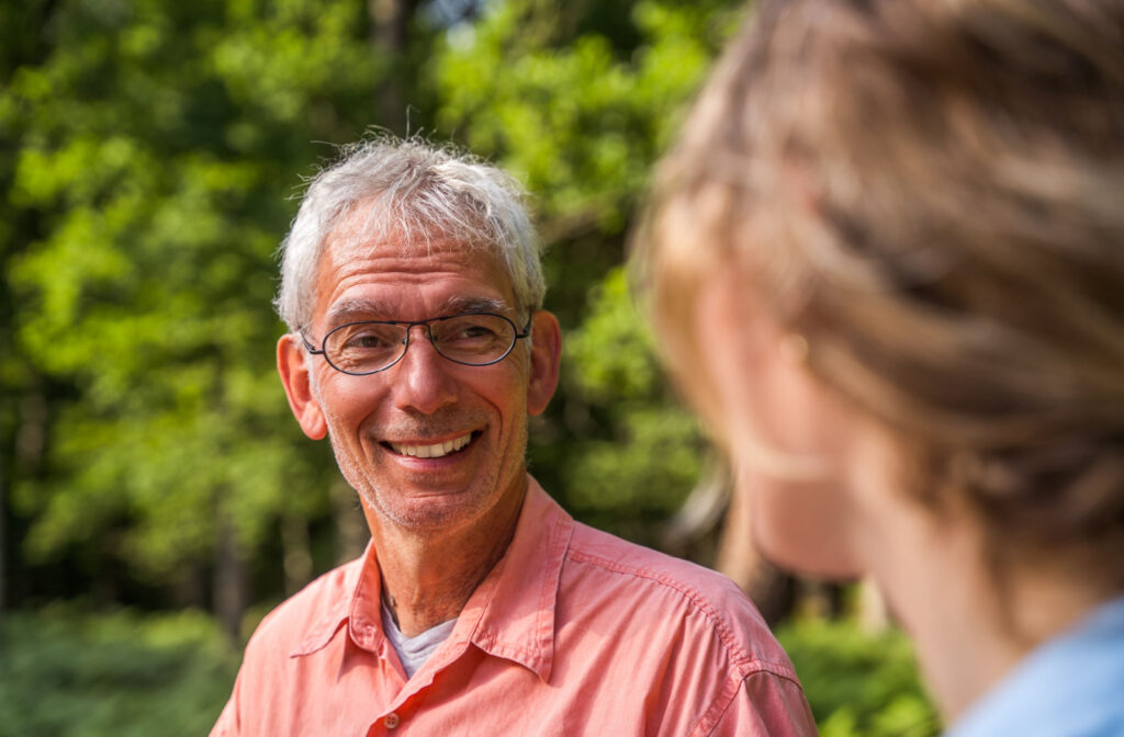 A senior man and his daughter smiling and talking to each other in a park