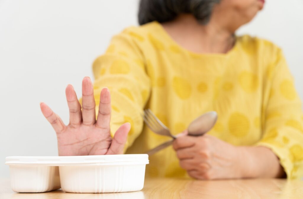 An older adult woman pushing away a ready meal
