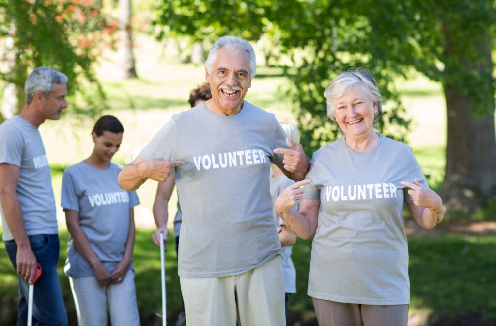 A group of older adults smiling and pointing to their t-shirts that read 'Volunteer.'"