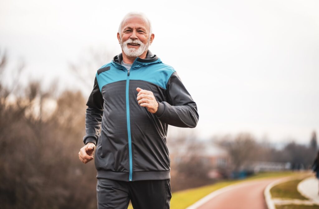 A smiling older adult jogging outdoors.